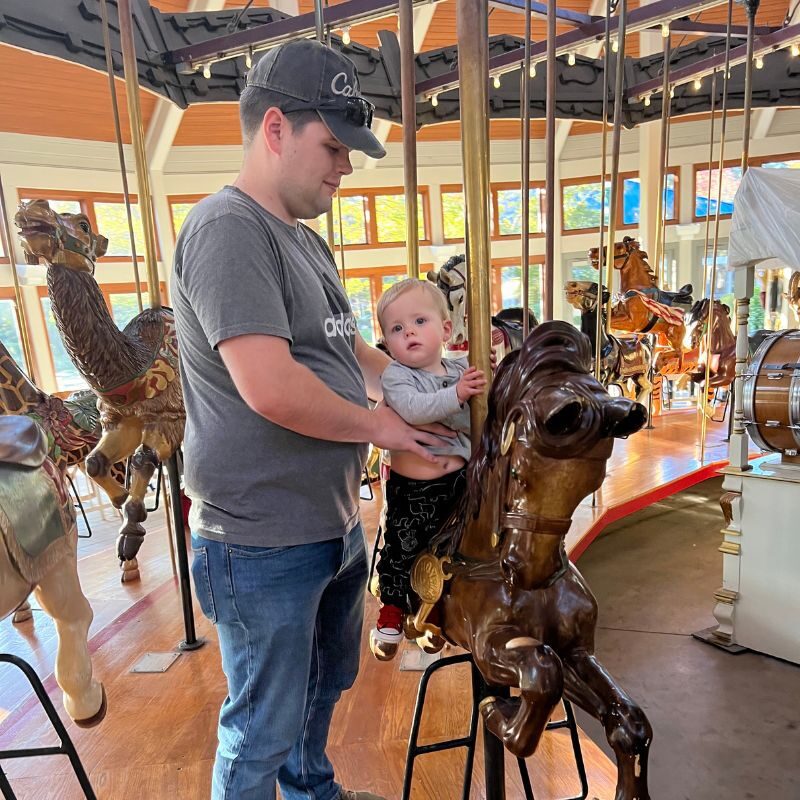 A father and son ride a carousel in Coolidge Park. 