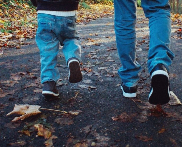 father and son on a nature trail surrounded by Fall leaves