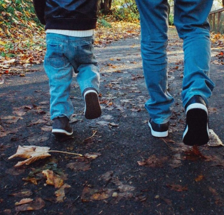 father and son on a nature trail surrounded by Fall leaves