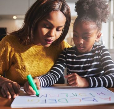 mother and daughter practicing writing alphabet