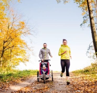 man and woman pushing a stroller and running