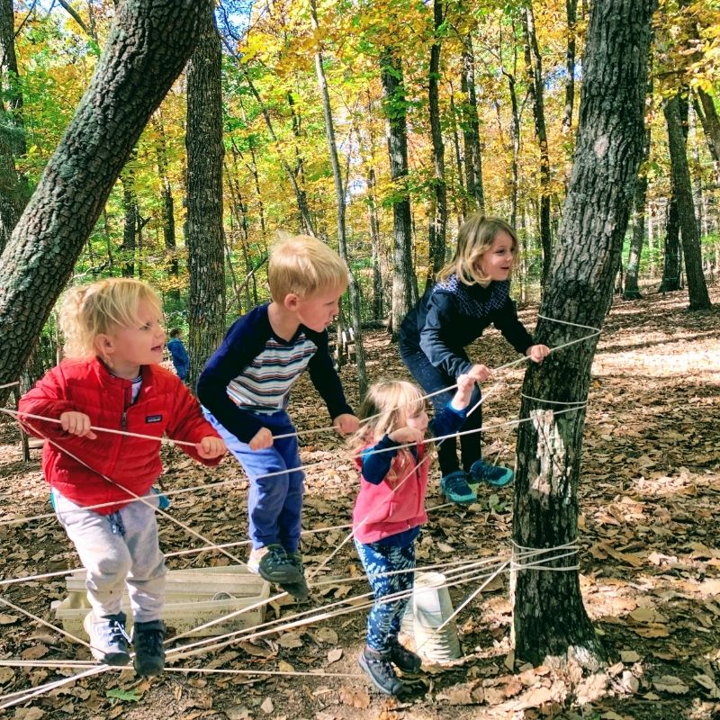 children playing in the woods on an obstacle course
