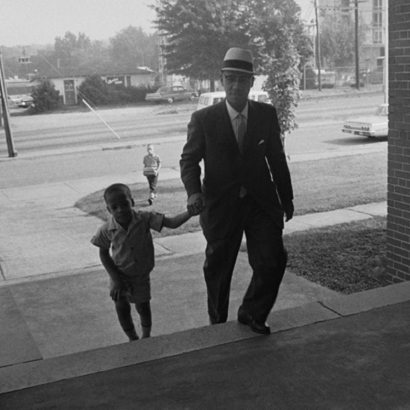 Sonnie Hereford IV walks with his father to school as the first black child to be enrolled in a public school in Alabama. 