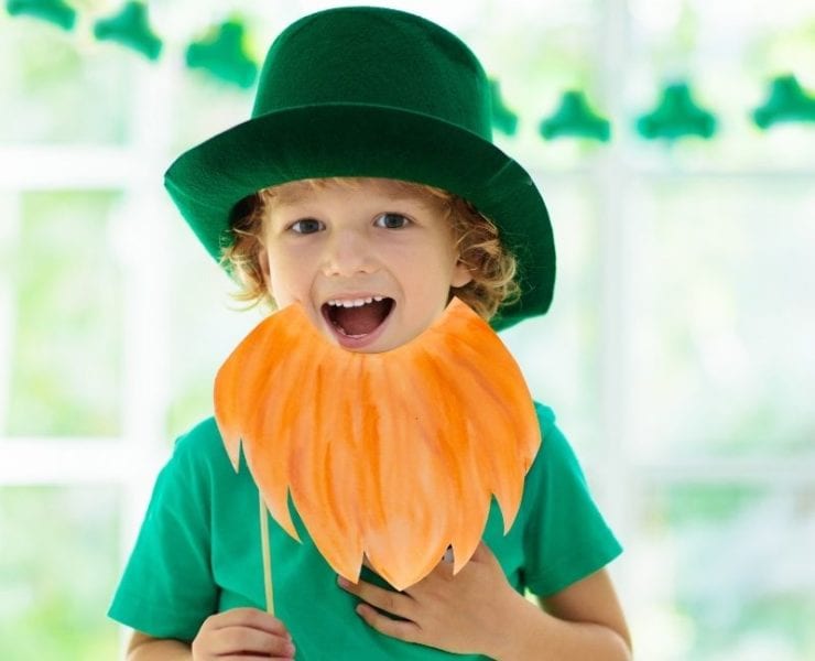 A young boy holds a paper beard and wears green as part of Saint Patrick's Day.