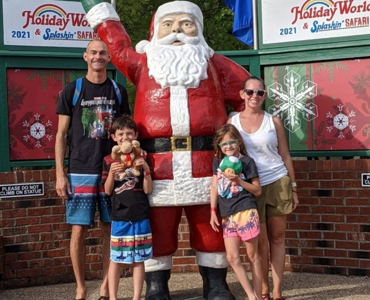 A family of four stands with a Santa statue at Holiday World.