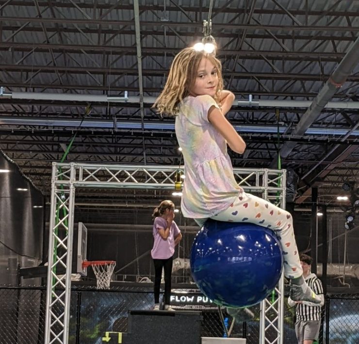 young girl on an indoor zip line