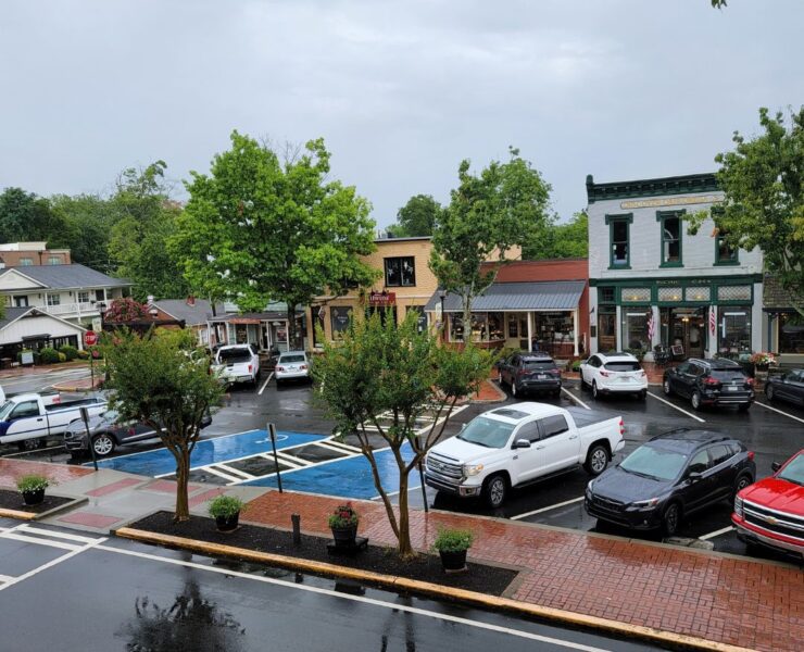Downtown Dahlonega includes several connected shops of varying colors and heights, with several cars parked on the street.