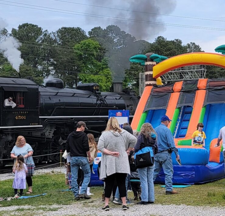 A large inflatable slide can be seen next to a parked black train engine at the Tennessee Valley Railroad Museum.