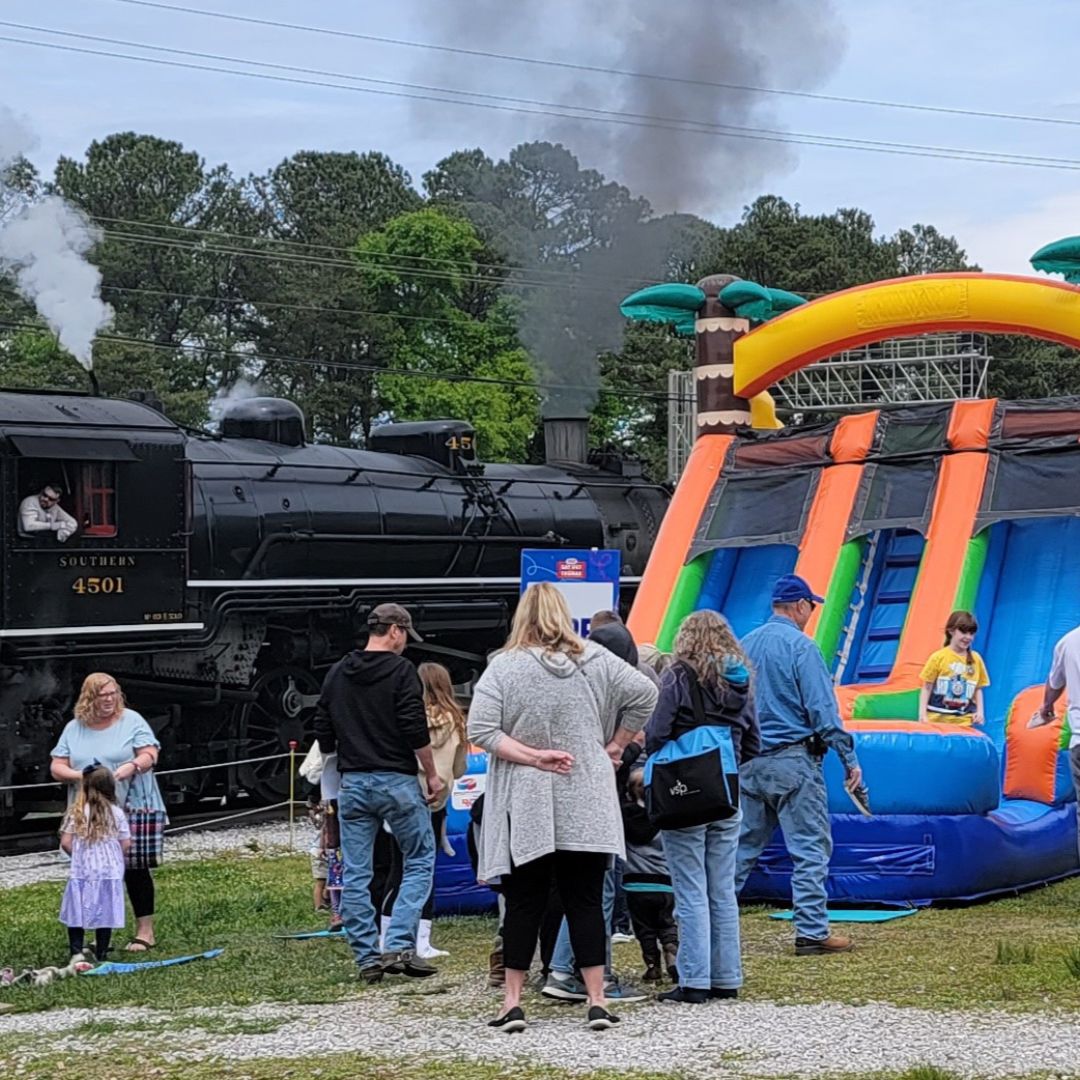 A large inflatable slide can be seen next to a parked black train engine at the Tennessee Valley Railroad Museum.
