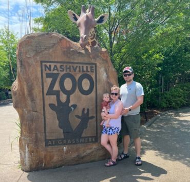 A young family stands outside the Nashville Zoo entrance.