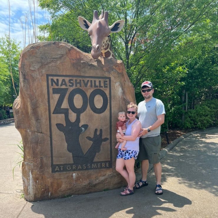 A young family stands outside the Nashville Zoo entrance.