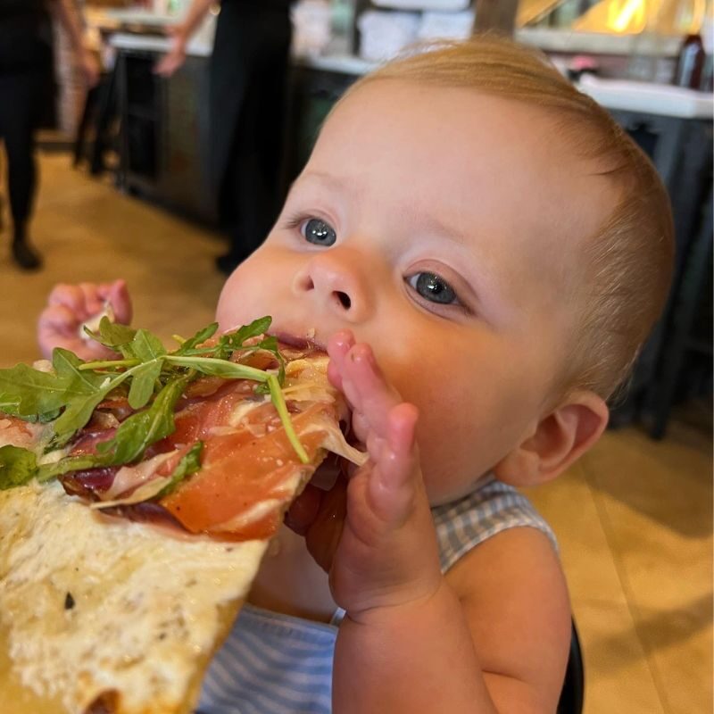 A toddler takes a large bite out of a slice of pizza at Grimaldi's Pizza in South Huntsville.