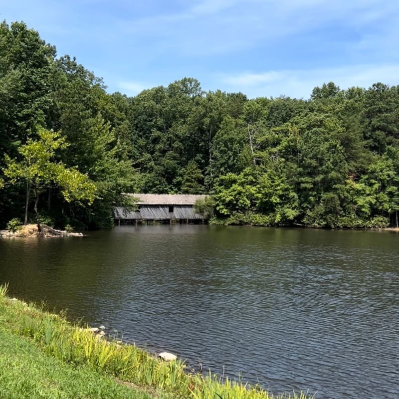 A covered bridge can be seen on the far side of a lake at Green Mountain Nature Trail.