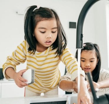two girls washing dishes at a kitchen sink