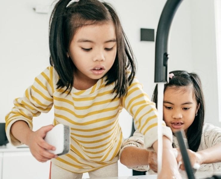 two girls washing dishes at a kitchen sink