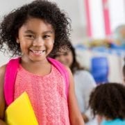 young girl in school classroom with backpack