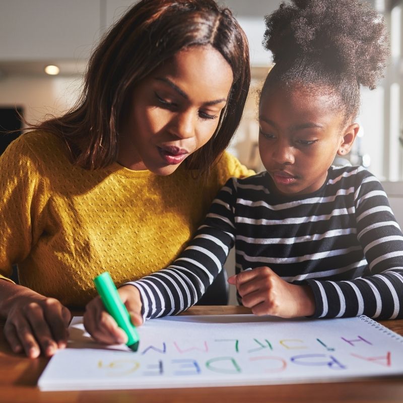 mother and daughter practicing writing alphabet