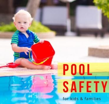 baby boy in a swimsuit playing near the edge of a swimming pool