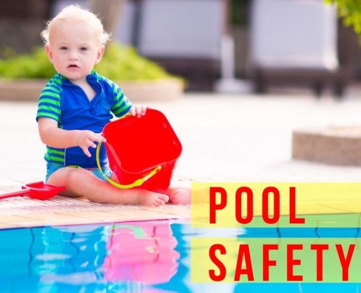 baby boy in a swimsuit playing near the edge of a swimming pool