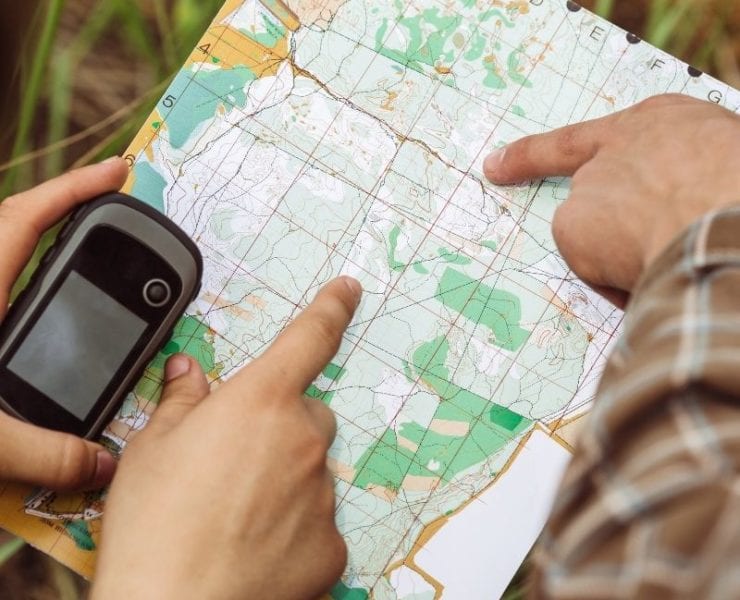 hands exploring a map while geocaching in the woods