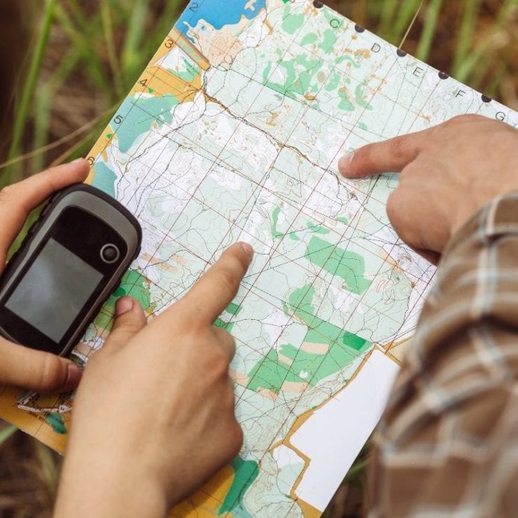 hands exploring a map while geocaching in the woods