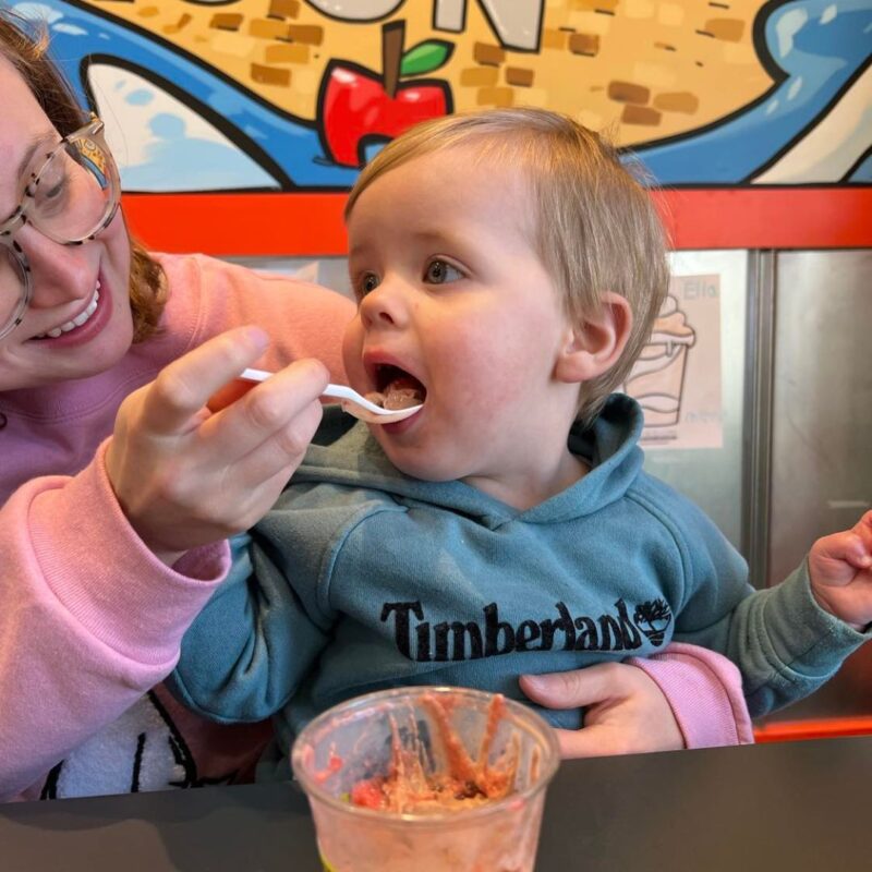 A toddler boy in a teal hoodie takes a bite out of a frozen treat at Jeremiah's Italian Ice in Madison. 