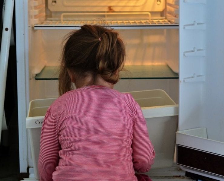 hungry child sitting in fron tof empty refrigerator