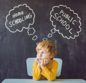 boy sitting at desk thinking about homeschool or public school