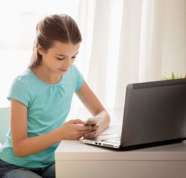 girl at desk with laptop computer and phone