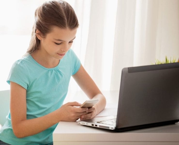 girl at desk with laptop computer and phone