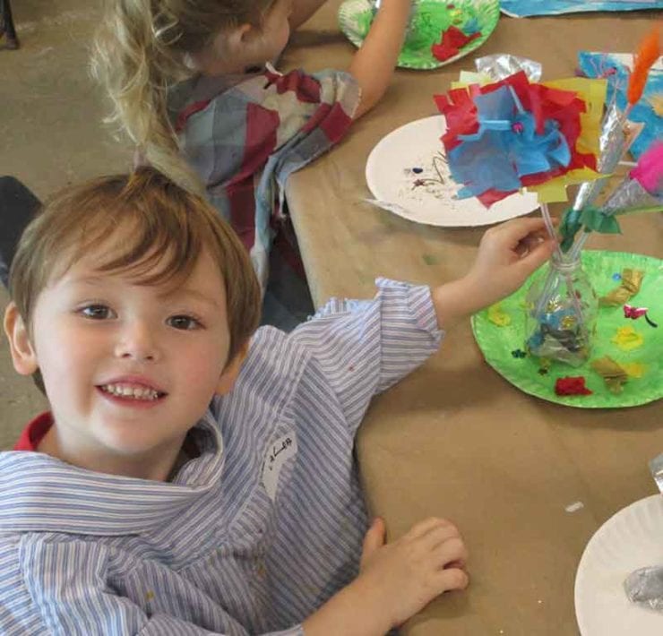 A young boy holds a colorful paper flower he created at the Huntsville Museum of Art.