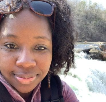 Zenovia Stephens standing in front of a waterfall