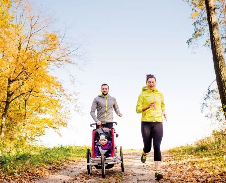 man and woman pushing a stroller and running