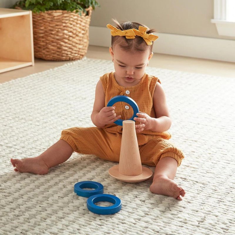 A toddler girl playing with a Montessori ring toy.