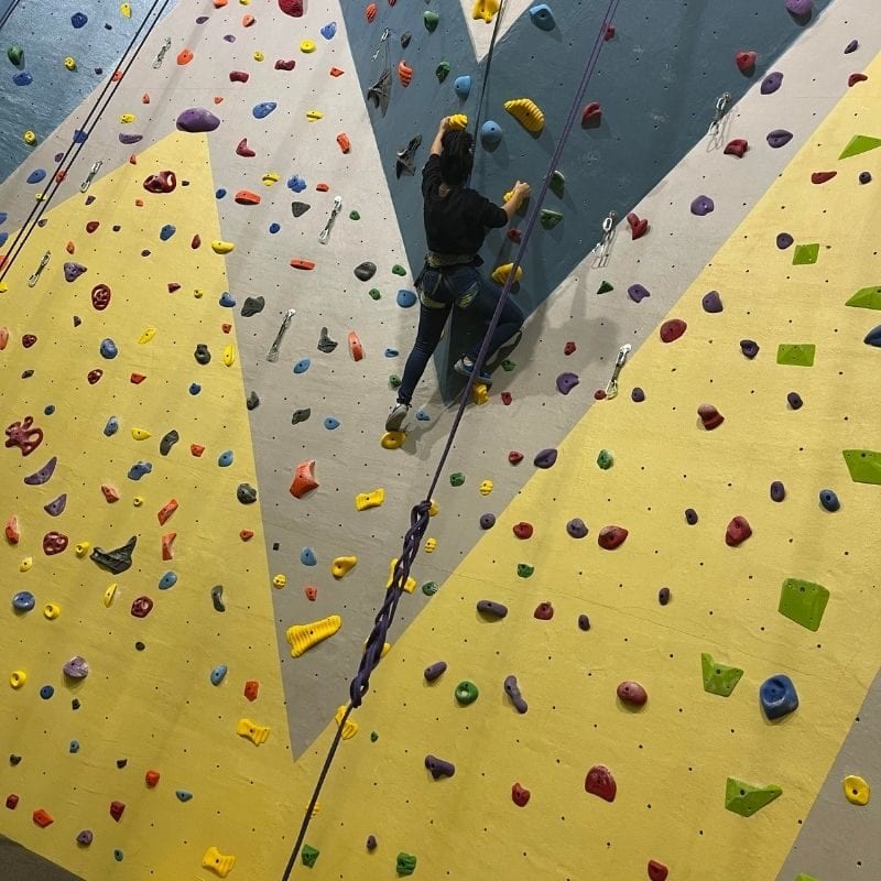 15-year-old Jordyn scales a rock climbing wall at Johnson Legacy Center.
