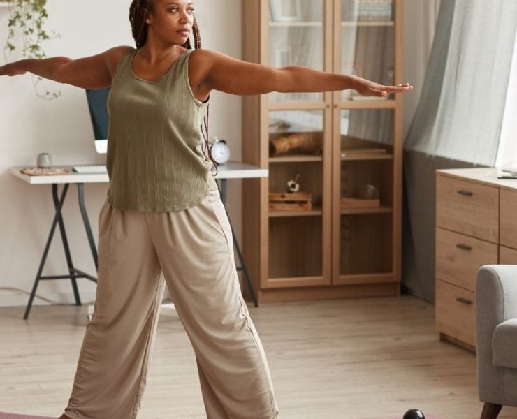black woman doing yoga exercises in her living room