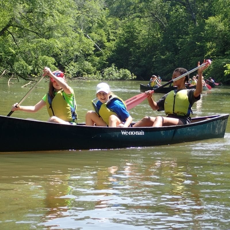 Three girls canoe down an Alabama paddle trail. 