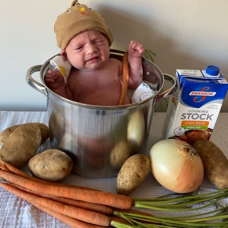 This cute DIY photoshoot idea features a baby in a turkey hat inside a large stock pot surrounded by chicken stock and veggies.