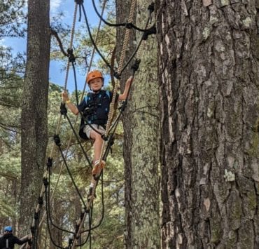 A boy scales a rope bridge during his visit to Raptor Aerial Adventure Park.