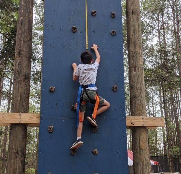 A boy climbs the rock climbing wall at GoFar USA.
