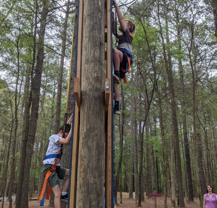 Two boys scale either side of the rock climbing wall at the GoFAR USA Park.