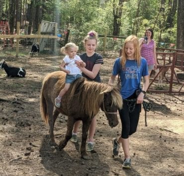A little girl enjoys a pony ride in the petting zoo section of GoFAR USA Park.