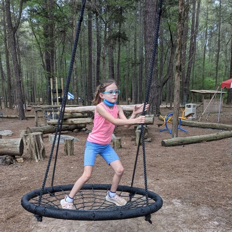 A girl swings in a large netted swing at GoFAR USA Park.