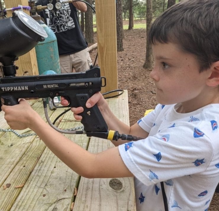 A boy aims his shot with the paint ball gun in the paint ball target area at GoFAR USA.