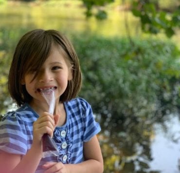 A young girl enjoys an ice pop in front of the Flint River during her family's float with NACK.