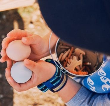 A young boy holds two eggs collected from the chickens on Haven Farms.