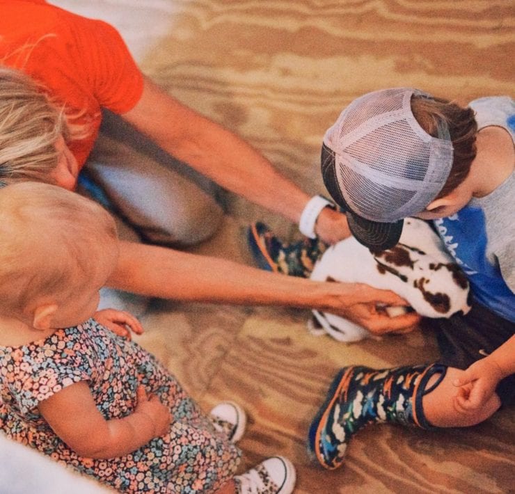 Two toddlers pet a white and brown speckled bunny at Haven Farms.