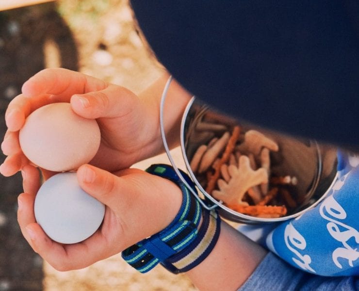 A young boy holds two eggs collected from the chickens on Haven Farms.