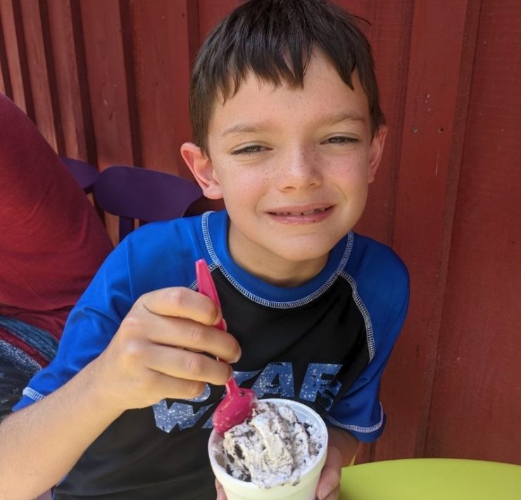 A young boy dips his spoon into a scoop of ice cream.