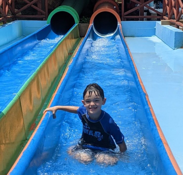 A young boy has made it to the end of an orange slide at Pirate's Bay Water park.